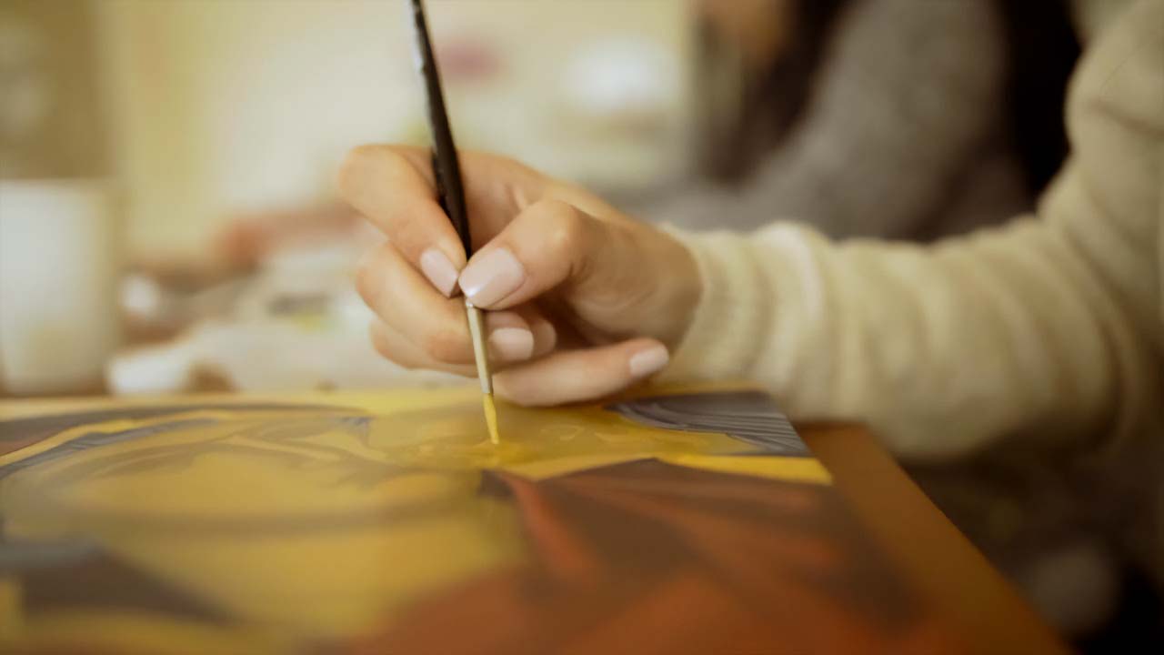 Fotografía de detalle: Mujer pintando un icono